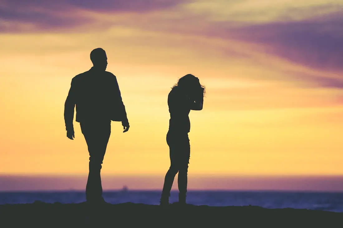 Silueta de un hombre y una mujer que se alejan uno del otro al atardecer