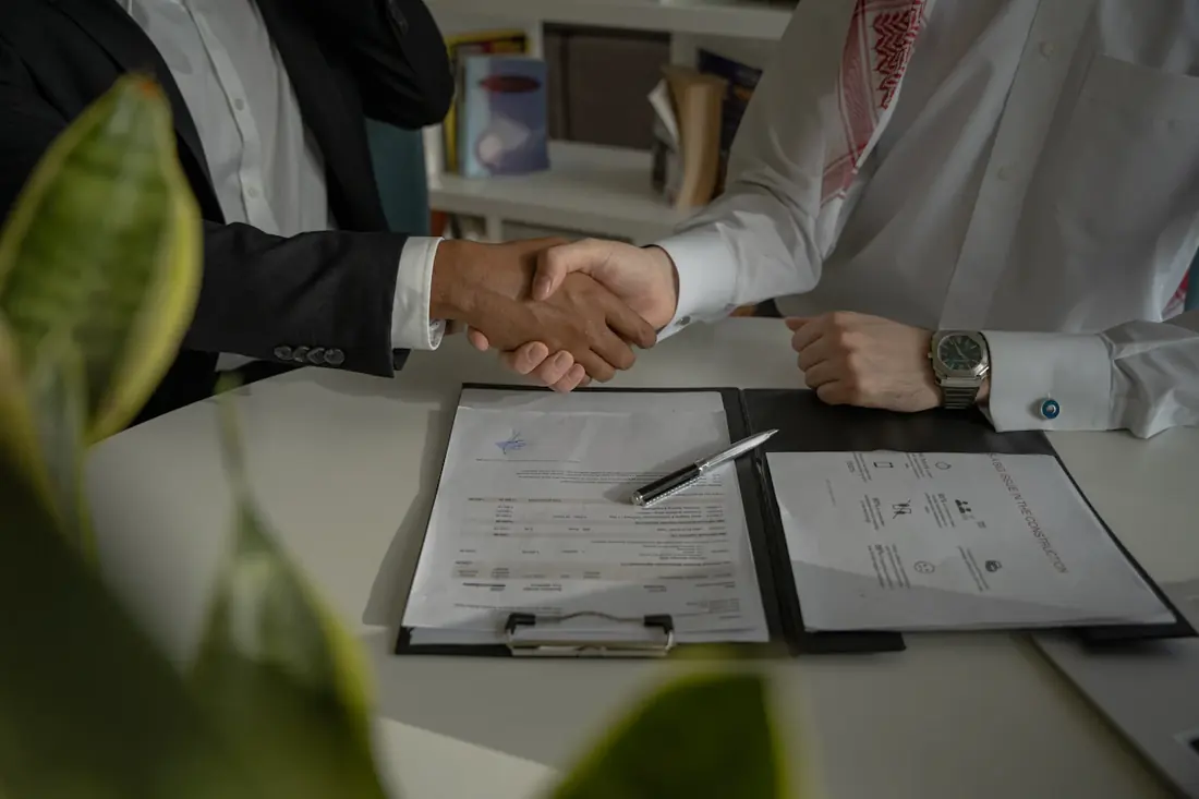 Dos personas se dan la mano sobre un convenio firmado